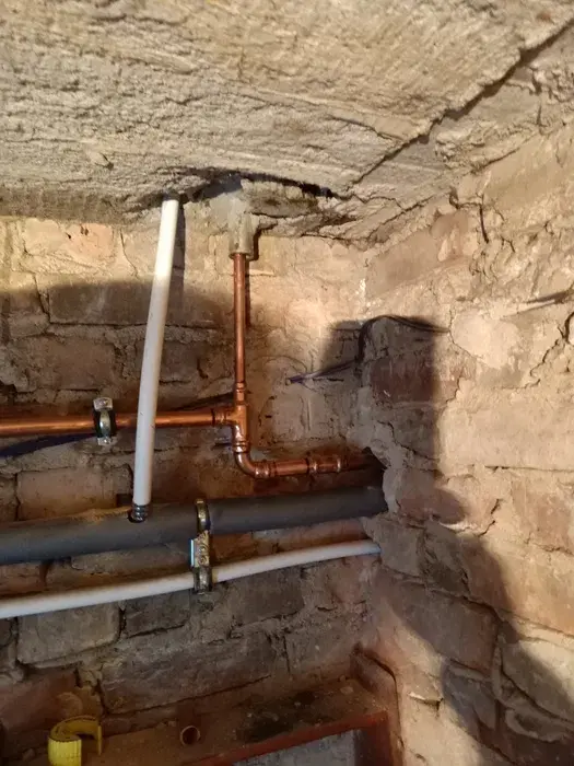 Nowy odcinek miedzianej instalacji gazowej w piwnicy z kamiennymi ścianami
